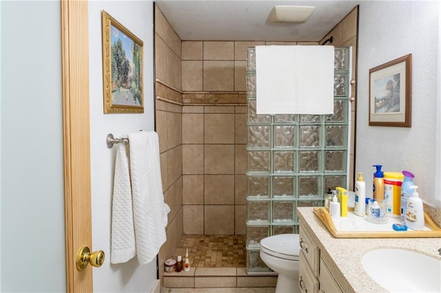 bathroom featuring a tile shower, vanity, and toilet