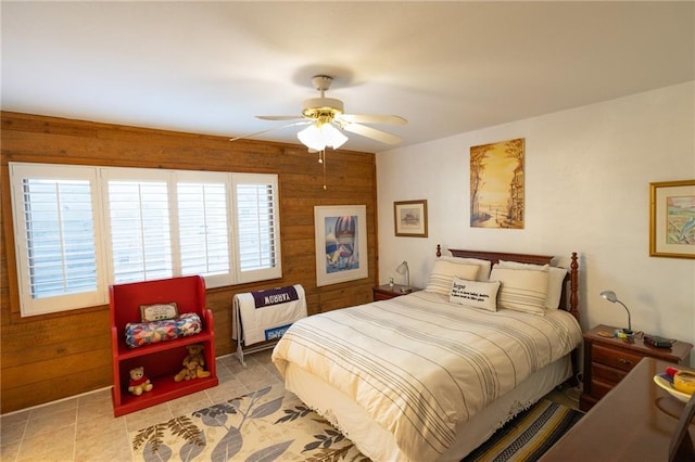 tiled bedroom featuring ceiling fan and wood walls