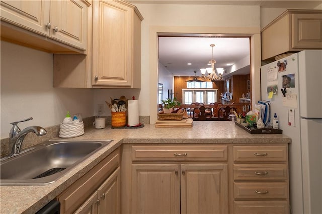 kitchen with sink, a chandelier, hanging light fixtures, white refrigerator, and dishwasher