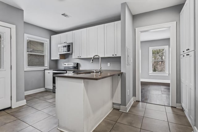 kitchen with appliances with stainless steel finishes, a sink, visible vents, and white cabinetry