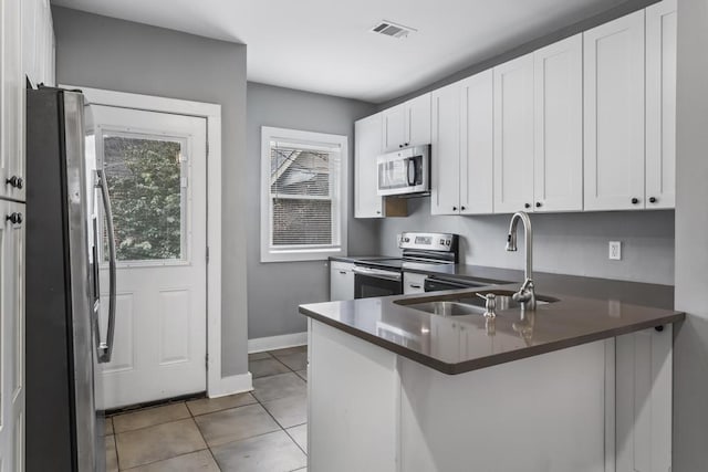 kitchen featuring dark countertops, plenty of natural light, stainless steel appliances, and a sink