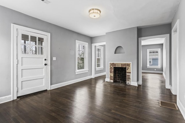 unfurnished living room featuring a fireplace, wood finished floors, visible vents, and baseboards