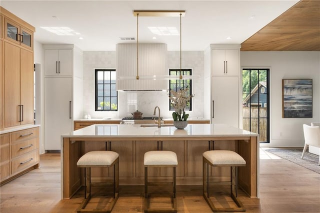 555 Orme Cir NE, Atlanta, GA 30306 - kitchen featuring a breakfast bar area, light wood-style floors, light countertops, a kitchen island with sink, and recessed lighting