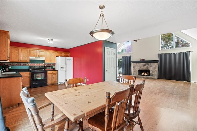 dining area with a fireplace, wood-type flooring, and sink