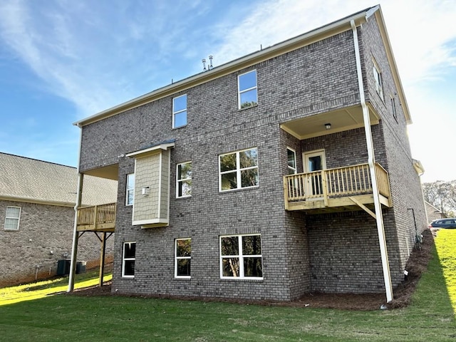 back of property featuring cooling unit, a lawn, a balcony, and brick siding