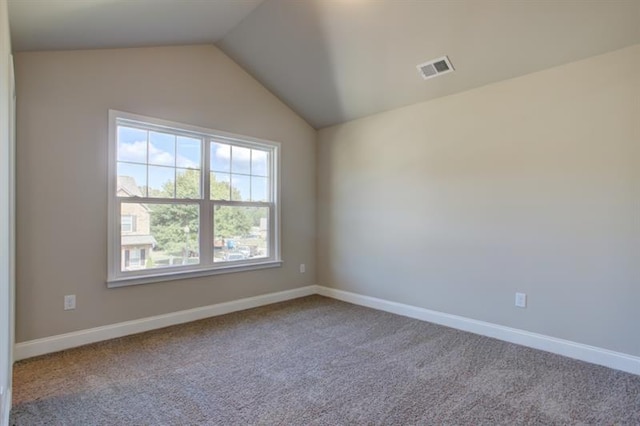 carpeted empty room with visible vents, baseboards, and lofted ceiling