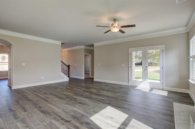 unfurnished living room featuring arched walkways, stairway, plenty of natural light, and baseboards