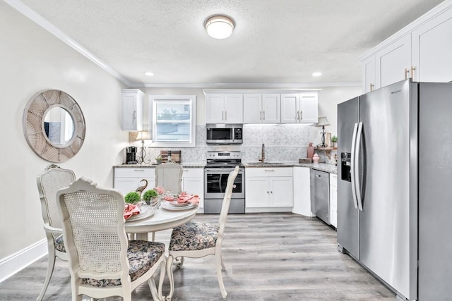 11 Poplar St, Porterdale, GA 30014 - kitchen featuring stainless steel appliances, a sink, ornamental molding, white cabinets, and a textured ceiling