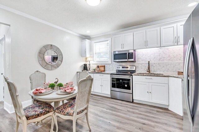 11 Poplar St, Porterdale, GA 30014 - kitchen with appliances with stainless steel finishes, a sink, white cabinets, ornamental molding, and tasteful backsplash