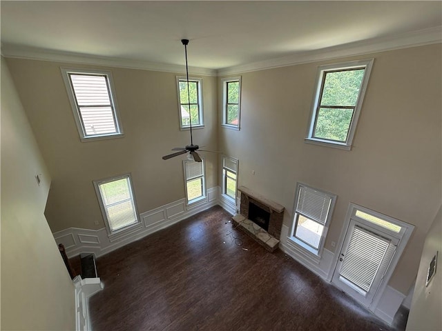 381 Plymstock Dr, Mcdonough, GA 30253 - unfurnished living room with dark wood-style floors, a fireplace with raised hearth, a towering ceiling, a ceiling fan, and crown molding