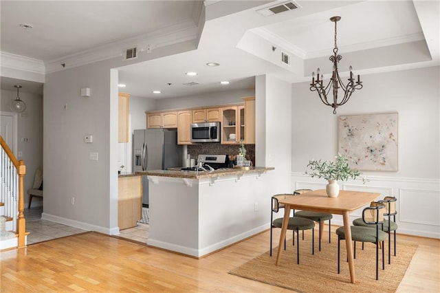 kitchen featuring light hardwood / wood-style flooring, stainless steel appliances, a breakfast bar, and kitchen peninsula