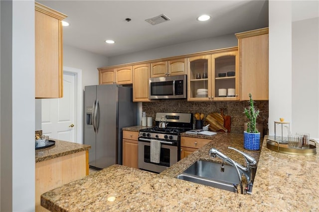 kitchen with sink, stainless steel appliances, light stone counters, decorative backsplash, and light brown cabinets