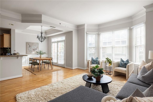 living room featuring light hardwood / wood-style floors, a notable chandelier, and ornamental molding