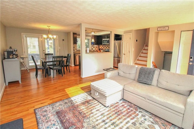 living room with hardwood / wood-style flooring, an inviting chandelier, and a textured ceiling