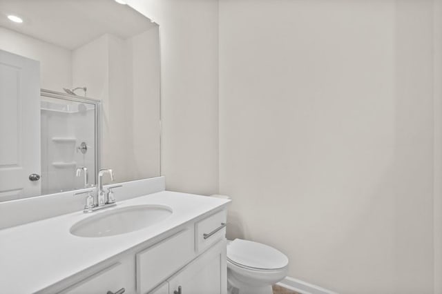 bathroom with toilet, vanity, and an enclosed shower