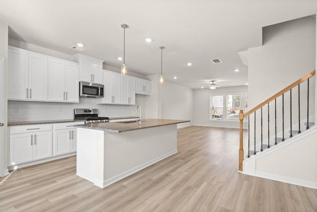 kitchen featuring ceiling fan, white cabinetry, a center island with sink, and stainless steel appliances