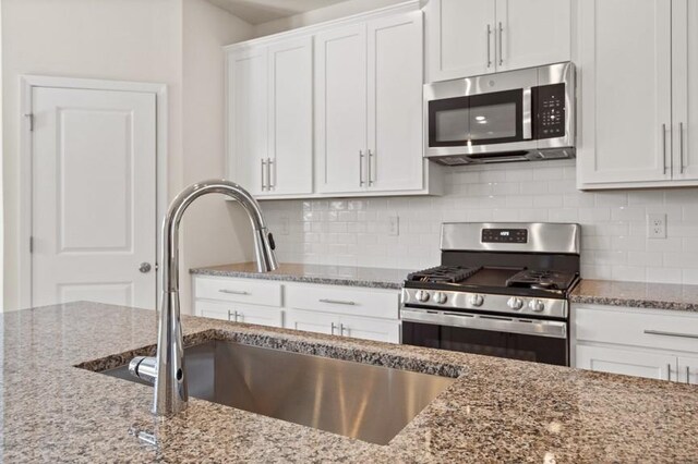 kitchen featuring sink, white cabinets, stainless steel appliances, and stone counters