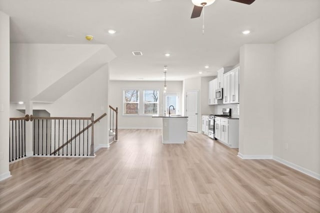 kitchen with white cabinetry, an island with sink, stainless steel appliances, decorative light fixtures, and sink