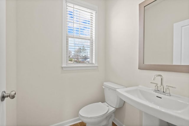 bathroom featuring toilet, a healthy amount of sunlight, and sink