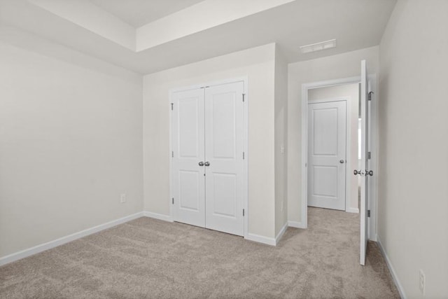 unfurnished bedroom featuring a closet and light colored carpet