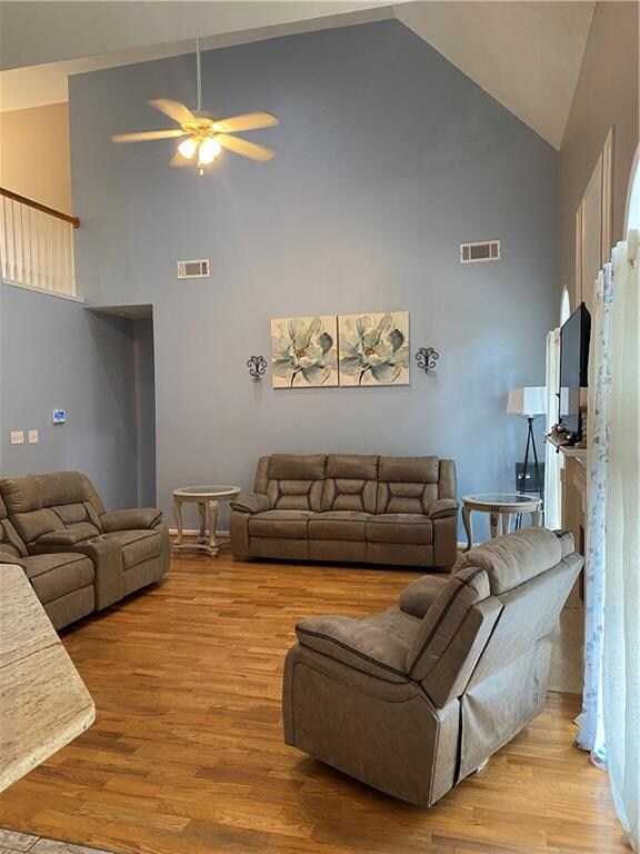 living room featuring light wood-type flooring, ceiling fan, and high vaulted ceiling