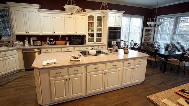 kitchen featuring dark hardwood / wood-style floors, hanging light fixtures, white cabinets, appliances with stainless steel finishes, and a center island