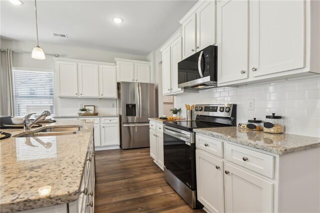 kitchen featuring light stone counters, dark wood-type flooring, hanging light fixtures, white cabinetry, and appliances with stainless steel finishes