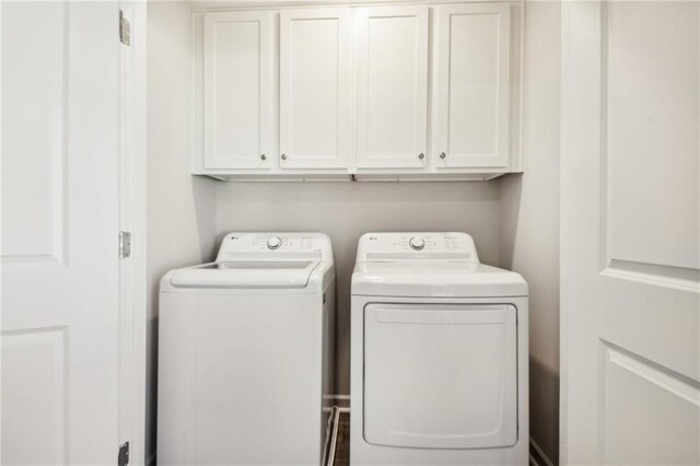 laundry area featuring washer and clothes dryer and cabinets