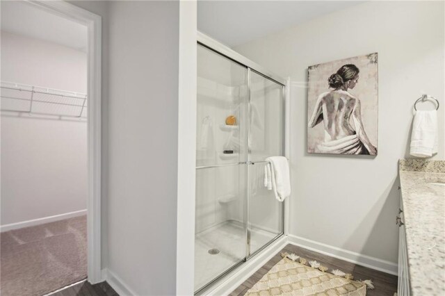 bathroom with hardwood / wood-style flooring, a shower with door, and vanity