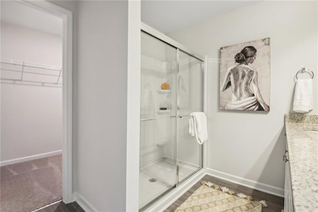 2527 Swan Lake Dr, Grayson, GA 30017 - full bathroom with vanity, wood finished floors, baseboards, a spacious closet, and a shower stall
