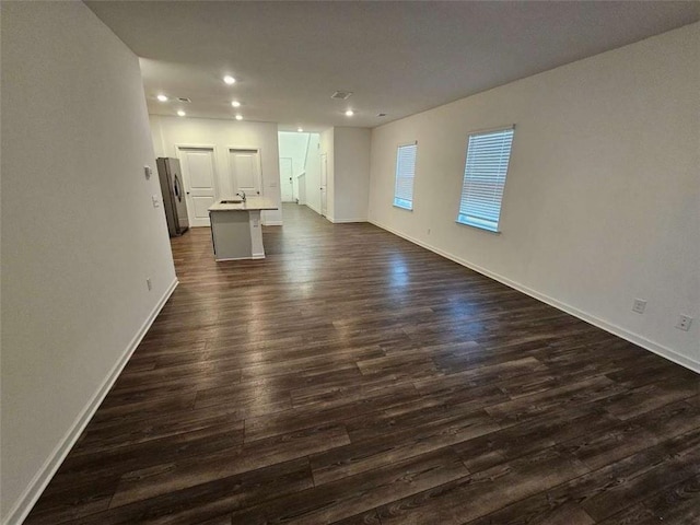 unfurnished living room with baseboards, dark wood-type flooring, and recessed lighting