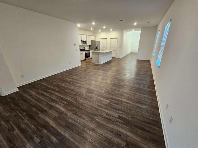 unfurnished living room with visible vents, baseboards, dark wood-style flooring, and recessed lighting