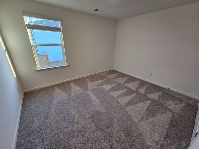 spare room featuring carpet floors, visible vents, and baseboards