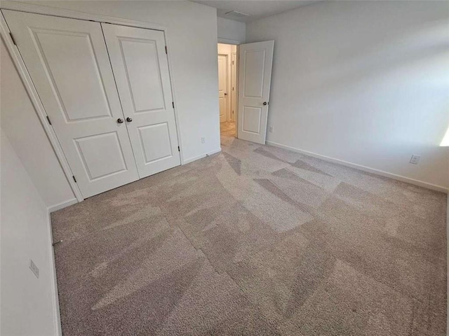 unfurnished bedroom featuring a closet, carpet flooring, and baseboards