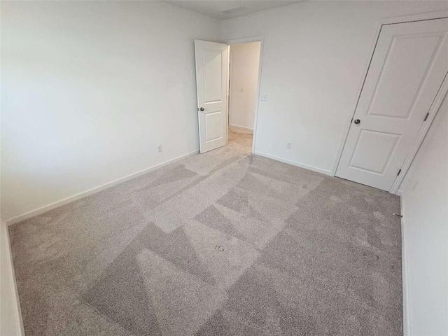 unfurnished bedroom featuring light colored carpet and baseboards