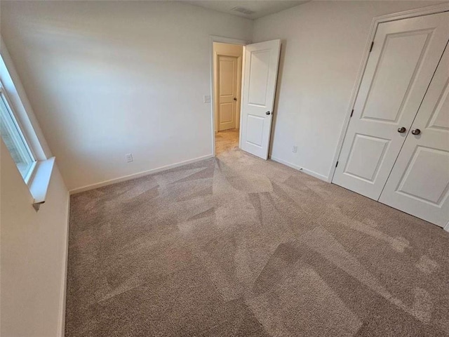 unfurnished bedroom featuring a closet, light carpet, and baseboards