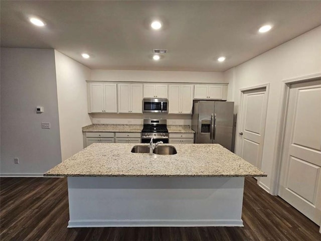 kitchen featuring stainless steel appliances, a sink, a kitchen island with sink, and white cabinetry