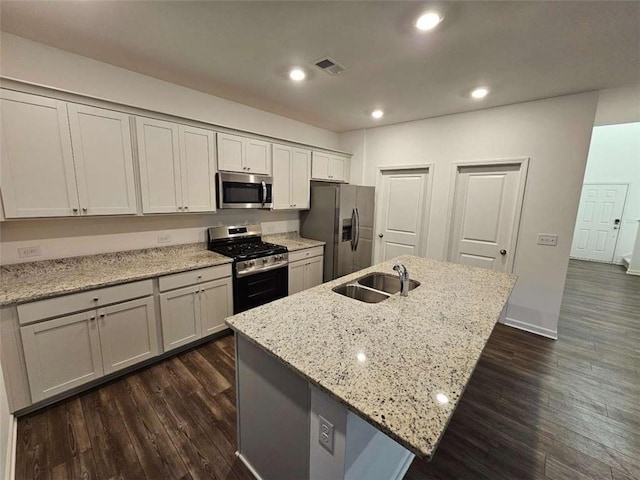 kitchen with visible vents, appliances with stainless steel finishes, light stone countertops, a kitchen island with sink, and a sink