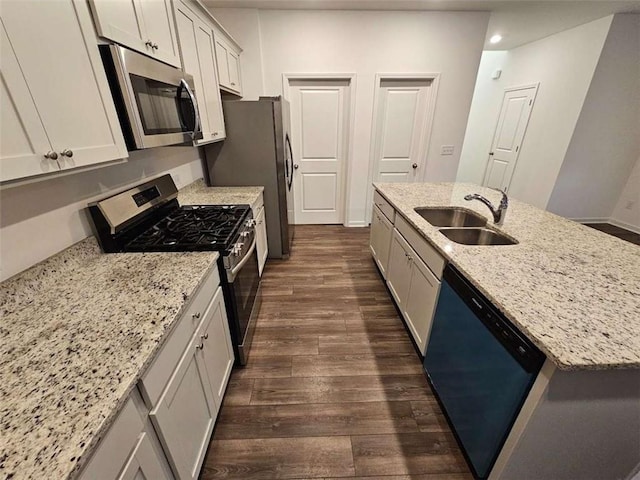 kitchen featuring white cabinets, light stone counters, stainless steel appliances, and a sink