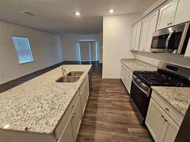 kitchen with a center island with sink, appliances with stainless steel finishes, and light stone counters