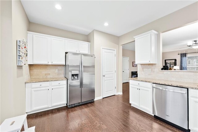 kitchen featuring stainless steel appliances, a sink, white cabinetry, backsplash, and dark wood-style floors