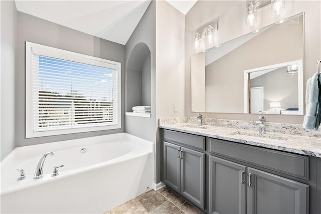 bathroom featuring double vanity, a sink, and a bath