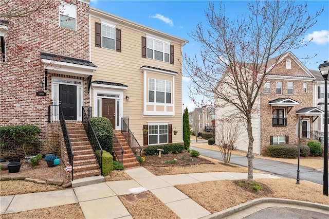 townhome / multi-family property featuring a residential view, a standing seam roof, brick siding, and metal roof