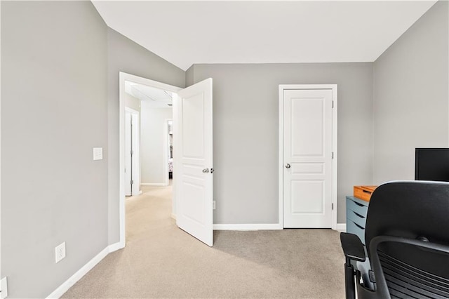 office space with attic access, baseboards, vaulted ceiling, and light colored carpet