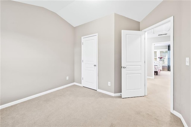 unfurnished bedroom with carpet floors, lofted ceiling, visible vents, and baseboards