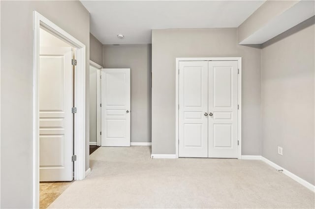 unfurnished bedroom with baseboards, a closet, and light colored carpet