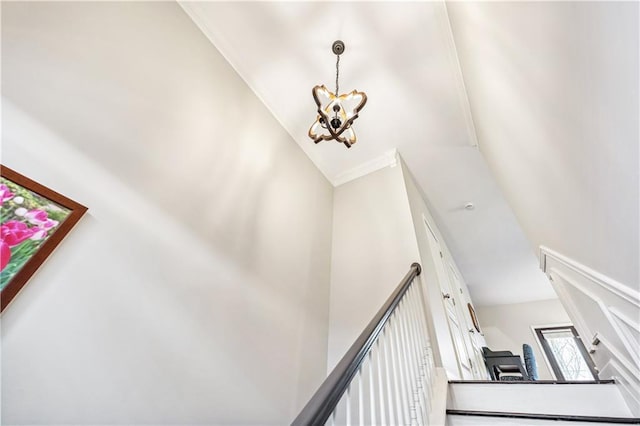 stairway with an inviting chandelier and ornamental molding