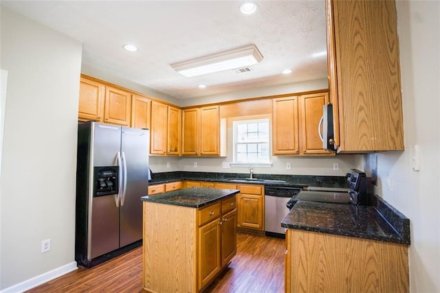 kitchen with a kitchen island, appliances with stainless steel finishes, dark wood-style floors, and a sink