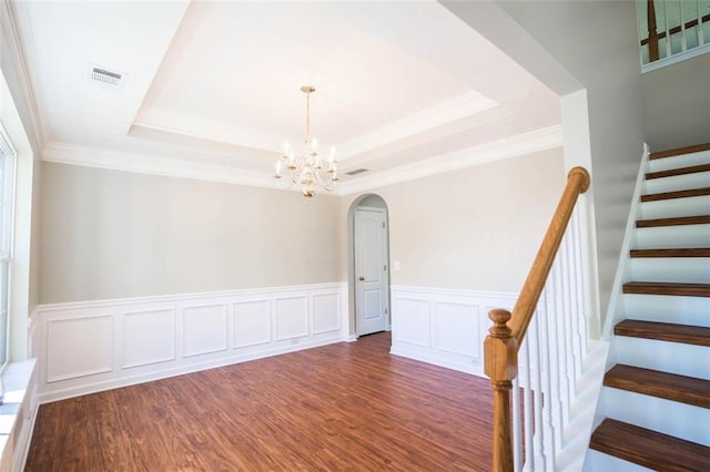 empty room with wood finished floors, visible vents, arched walkways, stairs, and a notable chandelier