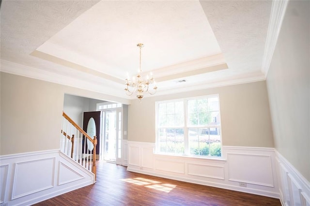 interior space featuring a raised ceiling, wood finished floors, a wealth of natural light, and an inviting chandelier